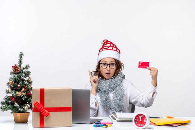 Trabalhadora de frente para o sexo feminino sentada diante de seu local de trabalho, segurando cartão de banco, negócio, trabalho, escritório de natal