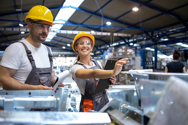 Trabalhadores da fábrica analisando os resultados da produção em um grande salão industrial