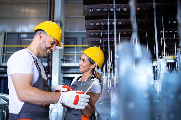 Trabalhadores de fábrica trabalhando juntos no corredor da linha de produção de metal industrial