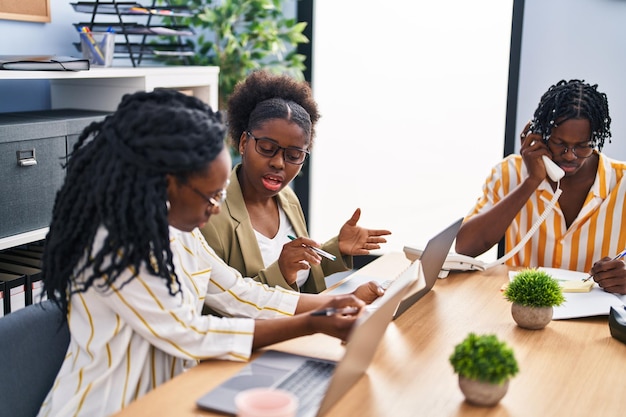 Trabalhadores de negócios de amigos afro-americanos sentados na mesa trabalhando no escritório