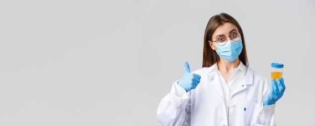 Trabalhadores de saúde de diagnóstico de pesquisa médica covid19 e conceito de quarentena Médico ou funcionário de laboratório clínico segurando amostra de urina do paciente usa máscara médica e luvas polegar para cima