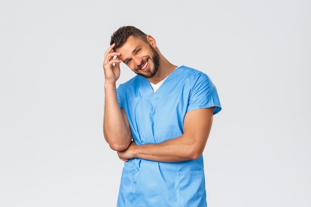 Trabalhadores de saúde, medicina, covid-19 e conceito de auto-quarentena pandêmica. Linda enfermeira masculina hispânica, médico de uniforme azul, sorrindo, câmera, cuidando de pacientes na clínica.