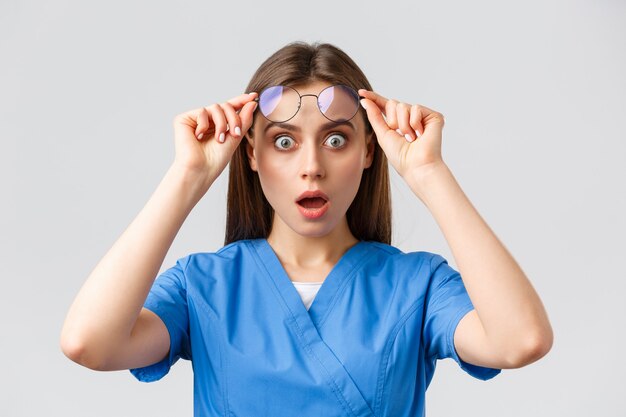 Trabalhadores de saúde, medicina, seguro e conceito de pandemia covid-19. Enfermeira surpresa ou chocada, médica em jaleco azul, boca aberta e óculos de tirar o fôlego atônita