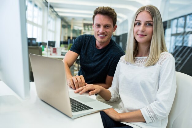 Trabalhadores de sorriso na frente de um computador portátil