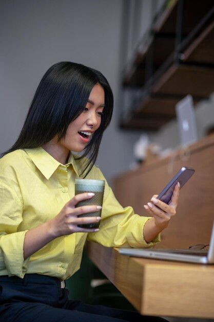 Trabalhadores por conta própria. Muito jovem mulher asiática na camisa amarela trabalhando em um laptop