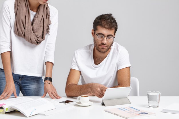 Trabalho em equipe. Foto sincera do belo jovem barbudo engenheiro-chefe verificando o projeto de sua irreconhecível empregada