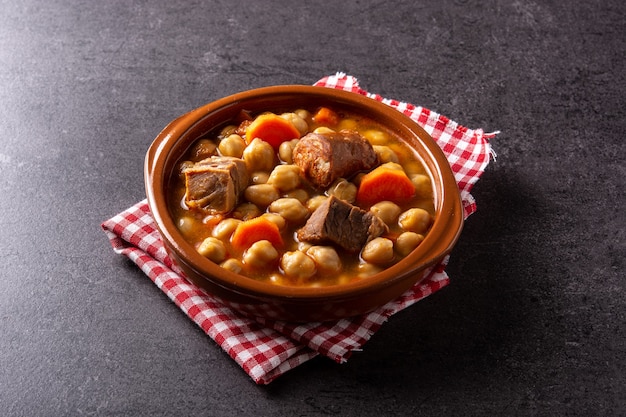 Tradicional cocido madrileno espanhol em tigela sobre fundo preto