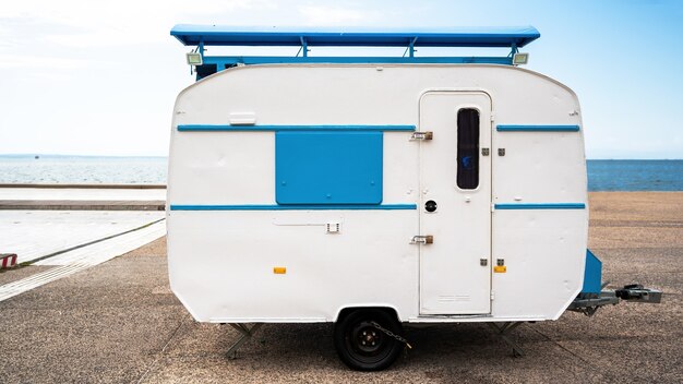 Trailer de viagem branco e azul com o mar ao fundo em Thessaloniki, Grécia