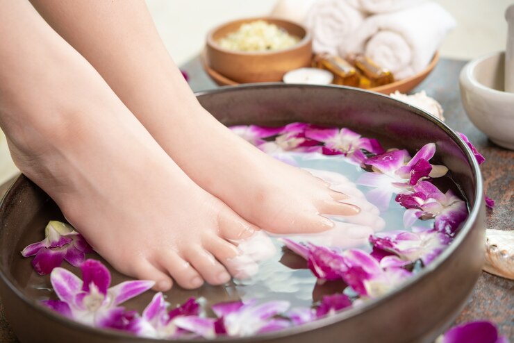 Foto grátis tratamento e produto spa para pés e mãos femininas. flores da orquídea em uma tigela de cerâmica.