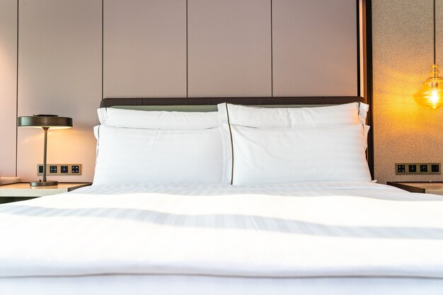 Travesseiro branco confortável e cobertor na decoração da cama no interior do quarto