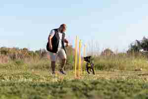 Foto grátis treinador de cães ensinando cachorro a correr através de obstáculos