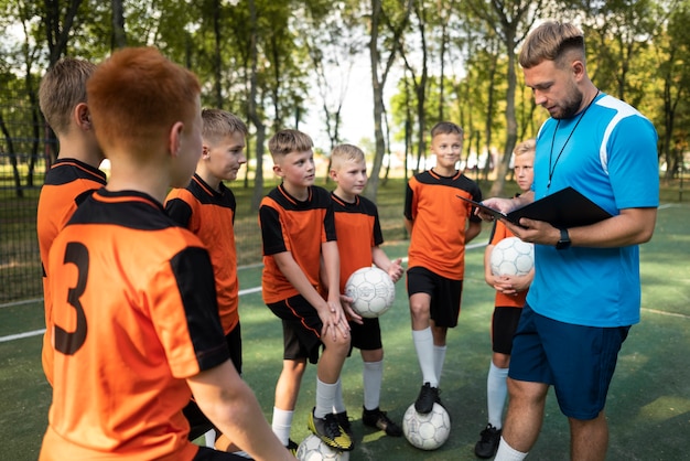 Foto grátis treinador de futebol ensinando seus alunos