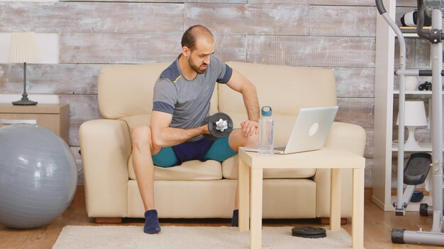 Treinador pessoal exercitando o músculo bíceps durante uma videochamada com clientes.