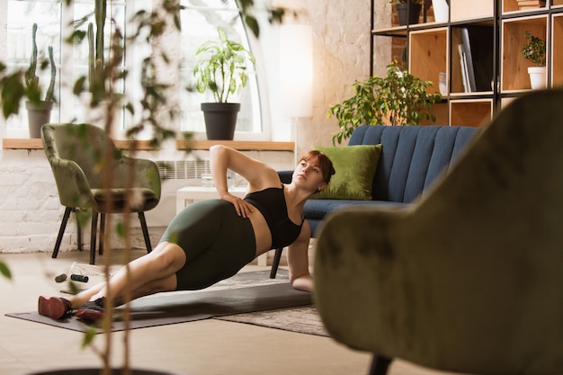 Treino com sofá. Mulher jovem a fazer exercício em casa