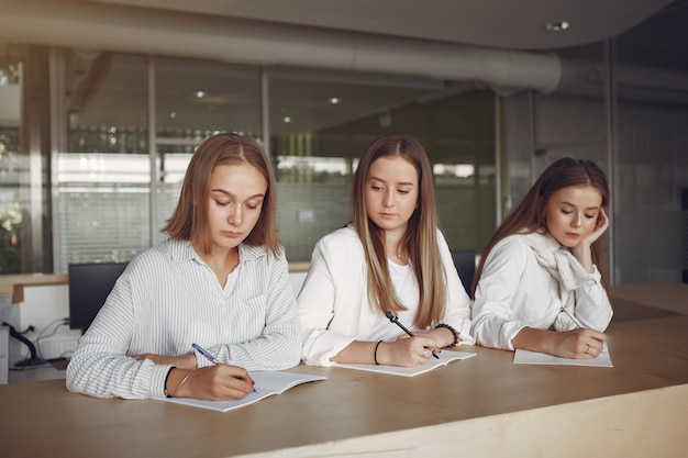 Três alunos sentados à mesa na sala de aula