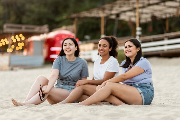 Três amigas sentadas na praia