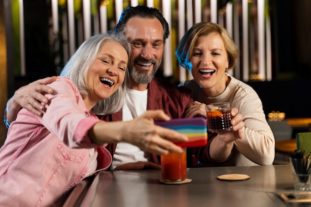 Três amigos mais velhos tirando uma selfie em um restaurante