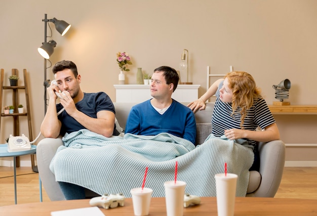 Três amigos no sofá com copos de cobertor e refrigerante