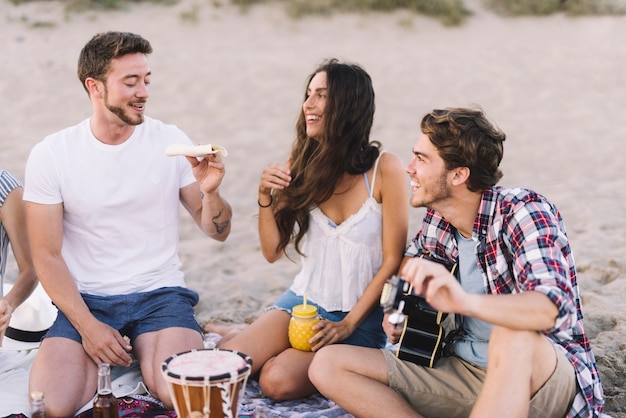 Três amigos rindo na areia