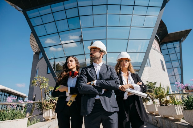 Três arquitetos de pé na frente do prédio