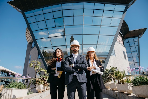 Três arquitetos em frente ao prédio com grandes janelas