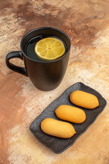 Três biscoitos e chá em uma xícara preta na mesa de cores misturadas