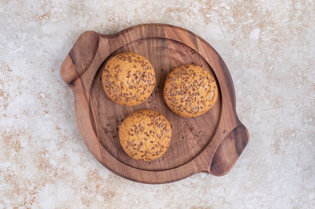 Três biscoitos em uma placa, na mesa de mármore.
