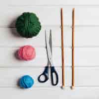 Foto grátis três bolas de lã, tesouras e agulhas