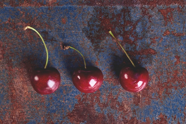 Foto grátis três cerejas maduras na velha mesa