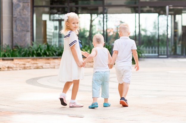 Três crianças andando e segurando as mãos ao ar livre