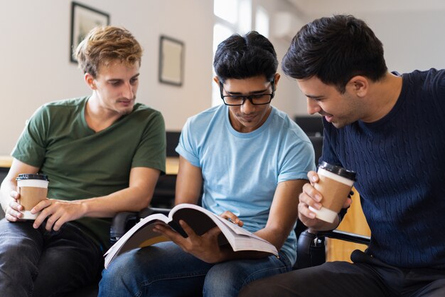 Três estudantes focados estudando juntos e bebendo