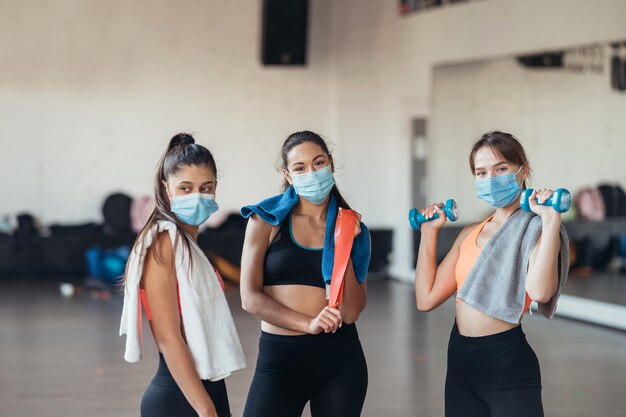 Três felizes garotas sorridentes positivas após o treino no ginásio. Estão olhando para a câmera. Horizontal.