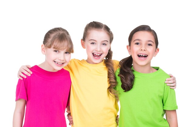 Três fofas fofas meninas sorridentes em t-shirts coloridas em pé - isolado no branco.