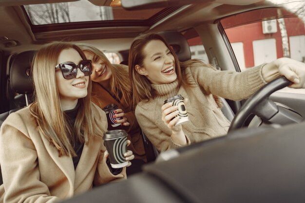 Três garotas sentado dentro do carro e tomando um café