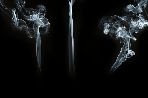 Três grandes silhuetas do fumo no fundo preto