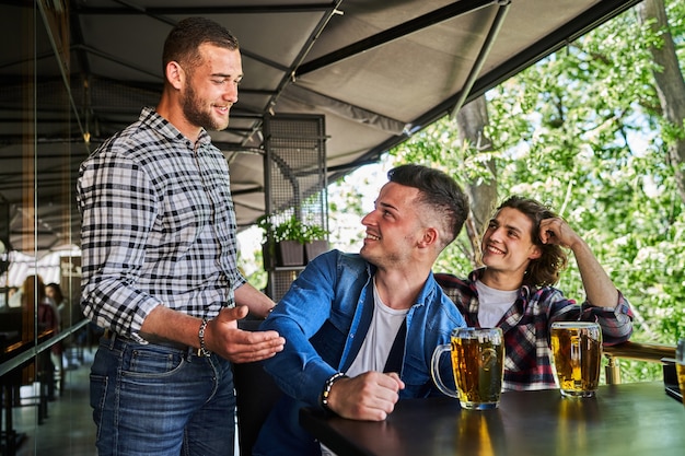 Três homens bonitos se encontram para beber cerveja em um bar.
