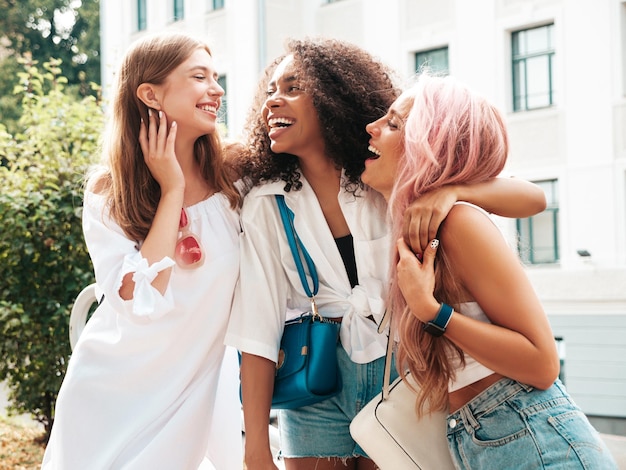 Três jovem linda mulher sorridente em roupas de verão da modamulheres multirraciais despreocupadas sexy posando no fundo da ruamodelos positivos se divertindo em óculos de sol alegre e feliz