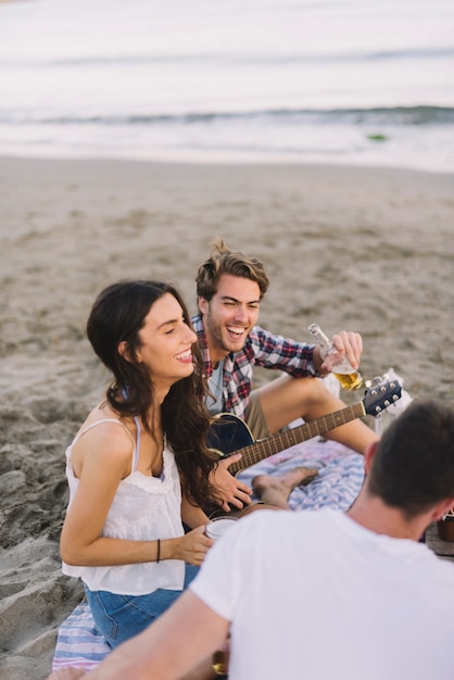 Foto grátis três jovens amigos sentados na praia