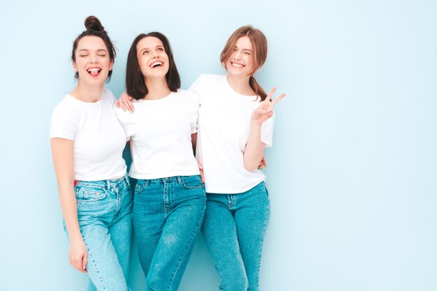 Três jovens lindas e sorridentes mulheres hippie no mesmo verão, camiseta branca e roupas jeans