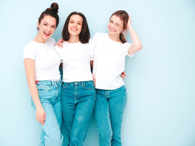 Três jovens lindas e sorridentes mulheres hippie no mesmo verão, camiseta branca e roupas jeans