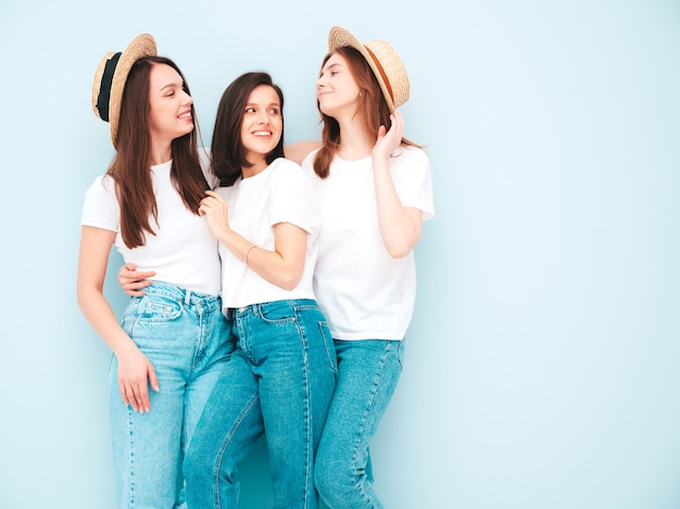 Três jovens lindas e sorridentes mulheres hippie no mesmo verão, camiseta branca e roupas jeans