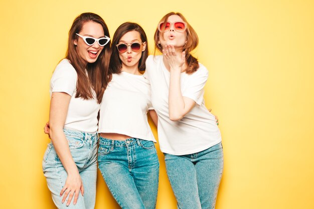Três jovens lindas sorrindo hipster feminina em uma camiseta branca da moda de verão e roupas jeans