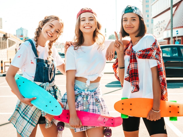 Três jovens sorridentes meninas bonitas com skates centavo colorido.