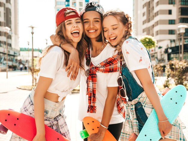 Três jovens sorridentes meninas bonitas com skates centavo colorido.