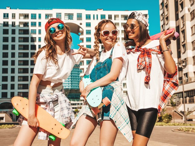 Três jovens sorridentes meninas bonitas com skates centavo colorido.