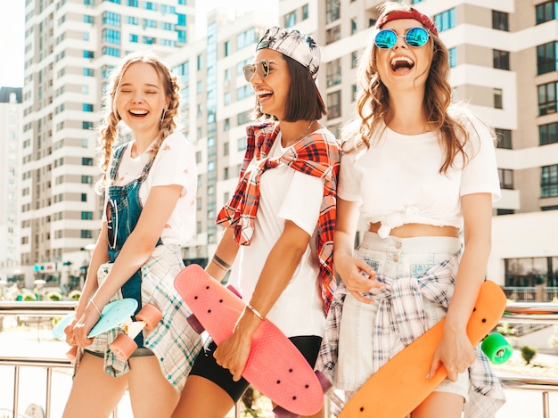 Três jovens sorridentes meninas bonitas com skates centavo colorido.