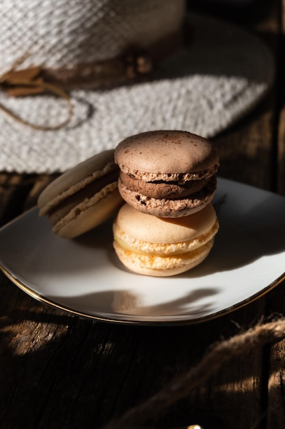 Três macaroons cremosos marrons em um fundo de madeira de placa dourada branca