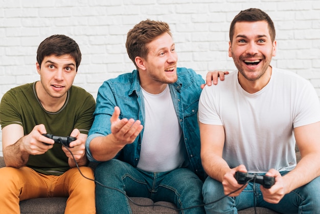 Três, macho, amigos, sentando, junto, desfrutando, a, videogame