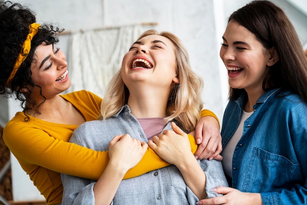 Três mulheres abraçadas rindo juntas