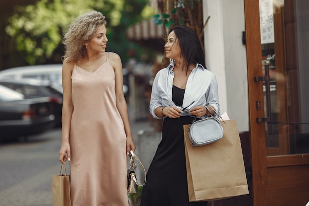 Três mulheres elegantes com sacolas de compras em uma cidade